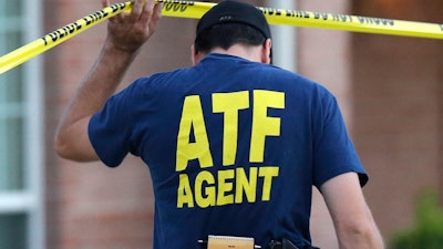 An ATF agent lifts crime scene tape, DeSoto, Texas, Aug. 8, 2013.