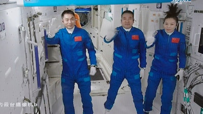 In this photo released by Xinhua News Agency, screen image captured at Beijing Aerospace Control Center in Beijing, China on Oct. 16, 2021, shows three Chinese astronauts, from left, Ye Guangfu, Zhai Zhigang and Wang Yaping waving after entering the space station core module Tianhe. Three Chinese astronauts returned to Earth on Saturday, April 16, 2022, after six months aboard China's newest space station in the longest crewed mission to date for its ambitious space program.