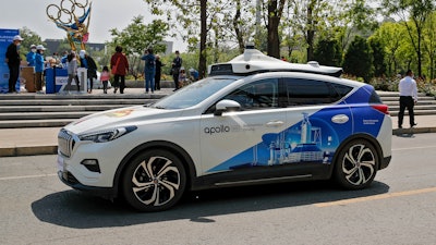 A Baidu Apollo Robotaxi passes its customer service counter setup at the Shougang Park in Beijing, Sunday, May 2, 2021. China has granted Chinese internet services company Baidu and a rival autonomous car company, Pony.ai, permits to provide driverless ride-hailing services to the public in Beijing, a significant regulatory step in the country's pursuit of driverless technology.