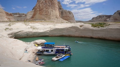 In this July 30, 2021, photo, a houseboat rests in a cove at Lake Powell near Page, Ariz. Federal water officials have announced that they will keep hundreds of billions of gallons of Colorado River water inside Lake Powell instead of letting it flow downstream to southwestern states and Mexico. U.S. Assistant Secretary of Water and Science Tanya Trujillo said Tuesday, May 3, 2022, that the move would allow the Glen Canyon Dam to continue producing hydropower while officials strategize how to operate the dam with a lower water elevation.