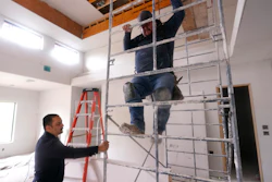 Joshua Correa, left, steadies a scaffolding for Samuel as they work at a home under construction in Plano, Texas, May 3, 2022.