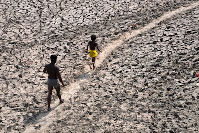 A man and a boy walk across the almost dried up bed of river Yamuna following hot weather in New Delhi, India, Monday, May 2, 2022. According to a report released by the World Meteorological Organization on Monday, May 9, 2022, the world is creeping closer to the warming threshold international agreements are trying to prevent, with nearly a 50-50 chance that Earth will temporarily hit that temperature mark within the next five years.