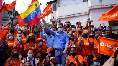 Venezuela opposition leader Juan Guaido poses for a group photo with residents after presenting his unity plan for Venezuelans, in Maiquetia, Venezuela, Saturday, Feb. 19, 2022. The faction of the Venezuelan opposition backed by the United States says it plans to hold primary contests next year to choose a presidential candidate for the planned 2024 election.
