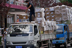 Workers load boxes of goods from a truck outside a wholesale clothing mall in Beijing on Tuesday, June 14, 2022. China's factory output rebounded in May, adding to a recovery from the latest COVID-induced economic slump after controls that shut down Shanghai and other industrial centers eased.