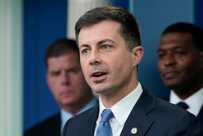 Transportation Secretary Pete Buttigieg, center, speaks during a briefing at the White House in Washington, May 16, 2022, as Labor Secretary Marty Walsh, left, and Environmental Protection Agency administrator Michael Regan, right, listen. Buttigieg says he is pushing airlines to hire more customer-service people and take other steps to help travelers this summer.