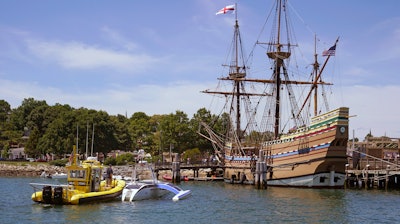 Brett Phaneuf, co-director of the Mayflower Autonomous Ship project, at left, stands on the deck of a tow boat as the Mayflower Autonomous Ship is guided next to the replica of the original Mayflower, Thursday, June 30, 2022, in Plymouth, Mass. The crewless robotic boat retraced the 1620 sea voyage of the Mayflower.