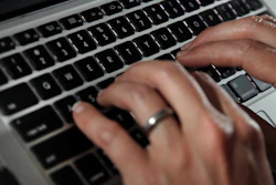 In this June 19, 2017, file photo, a person types on a laptop keyboard in North Andover, Mass. The availability of remote work has increased significantly in recent years, giving rise to the ability for telecommuters to buck travel norms. Remote work has blurred the line between business and personal travel, affording workers the flexibility to extend trips to fly on cheaper days.