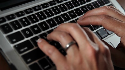 In this June 19, 2017, file photo, a person types on a laptop keyboard in North Andover, Mass. The availability of remote work has increased significantly in recent years, giving rise to the ability for telecommuters to buck travel norms. Remote work has blurred the line between business and personal travel, affording workers the flexibility to extend trips to fly on cheaper days.