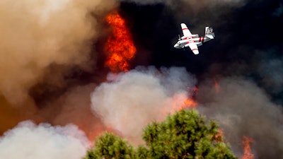 An air tanker flies past flames while battling the Oak Fire in Mariposa County, Calif., Sunday, July 24, 2022. Wildfires, floods and soaring temperatures have made climate change real to many Americans. Yet a sizeable number continue to dismiss the scientific consensus that human activity is to blame. That's in part because of a decades-long campaign by fossil fuel companies to muddy the facts and promote fringe explanations.