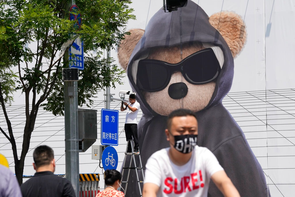 A worker installs a surveillance camera outside a mall, Friday, July 8, 2022, in Beijing. China's economic growth plunged to 0.4% over a year earlier in the latest quarter after Shanghai and other cities were shut down to fight coronavirus outbreaks, but the government said a 'stable recovery' is underway.