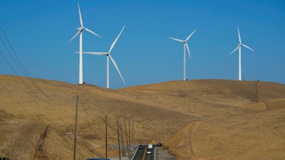 Vehicles move down Altamont Pass Road with wind turbines in the background in Livermore, Calif., Wednesday, Aug. 10, 2022. Congress is poised to pass a transformative climate change bill on Friday, Aug. 12. The crux of the long-delayed bill is to use incentives to accelerate the expansion of clean energy such as wind and solar power, speeding the transition away from the oil, coal and gas that largely cause climate change.