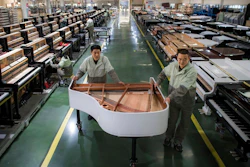In this photo released by Xinhua News Agency, workers transfer a half-assembled piano at a production factory of Parsons Music Corporation in Yichang, central China's Hubei Province, on Nov. 23, 2021. Chinese manufacturing’s recovery from anti-virus shutdowns faltered in July as activity sank, a survey showed Sunday, July 31, 2022, adding to pressure on the struggling economy in a politically sensitive year when President Xi Jinping is expected to try to extend his time in power.