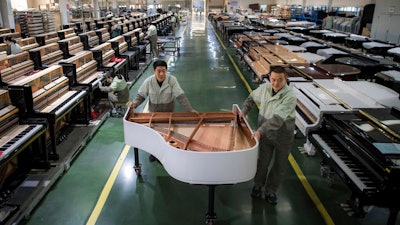 In this photo released by Xinhua News Agency, workers transfer a half-assembled piano at a production factory of Parsons Music Corporation in Yichang, central China's Hubei Province, on Nov. 23, 2021. Chinese manufacturing’s recovery from anti-virus shutdowns faltered in July as activity sank, a survey showed Sunday, July 31, 2022, adding to pressure on the struggling economy in a politically sensitive year when President Xi Jinping is expected to try to extend his time in power.