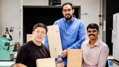 (from right) NTU Assoc Prof Aravind Dasari, NTU PhD graduate Dr Sheik Anees and PhD student Dean Seah. Assoc Prof Aravind is holding a coated piece of laminated timber while Dr Anees and Mr Seah are holding non-coated timber.