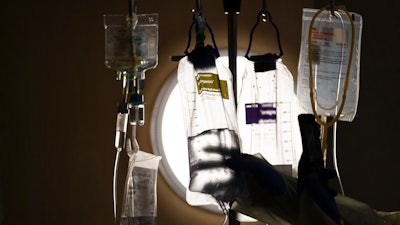 A nurse checks on IV fluids while talking to a COVID-19 patient at Providence Holy Cross Medical Center in Los Angeles, Dec. 13, 2021. A majority of adults in the U.S. say health care is not handled well in the country. That's according to a new poll from The Associated Press-NORC Center for Public Affairs Research.