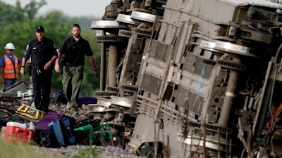Law enforcement personnel inspect the scene of an Amtrak train that derailed after striking a dump truck near Mendon, Mo., June 27, 2022.