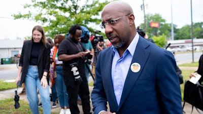 U.S. Sen. Rev. Raphael Warnock, wearing a 'I'm a Georgia Voter' sticker, leaves a press conference after casting his primary ballot Friday, May 6, 2022 in Atlanta, Ga., during early voting.