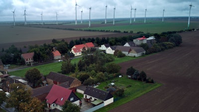 Wind turbines turn near the village of Feldheim, rear left, near Treuenbrietzen, Germany, Wednesday, Sept. 28, 2022.