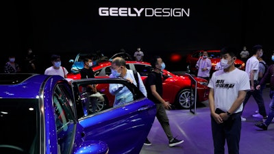Visitors look at cars produced by Geely at the Auto China 2020 show in Beijing on Sept. 27, 2020. Geely Holding Group, one of China's biggest independent automakers, has bought a 7.6% stake in British luxury brand Aston Martin Lagonda and said Friday, Sept. 30, 2022, that it looks forward to potential opportunities to collaborate.