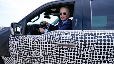 President Joe Biden stops to talk to the media as he drives a Ford F-150 Lightning truck at Ford Dearborn Development Center, May 18, 2021, in Dearborn, Mich. Biden, a self-described “car guy,'' often promises to lead by example by moving swiftly to convert the sprawling federal fleet to zero-emission electric vehicles.