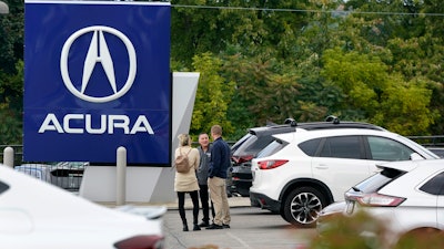 A salesman talks with customers in an Acura dealership lot in Wexford, Pa., on Sept. 29, 2022.