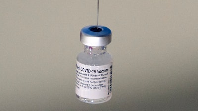 A syringe is placed into a vial of Pfizer-BioNTech vaccination at a COVID-19 clinic in Augusta, Maine, on Tuesday, Dec. 21, 2021.