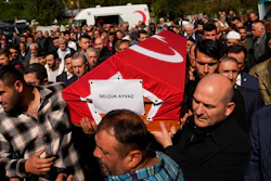 Turkey's Interior Minister Suleyman Soylu, right, helps a coffin covered with a Turkish flag of one of the miners killed in a coal mine explosion, during his funeral in Amasra, in the Black Sea coastal province of Bartin, Turkey, Saturday, Oct. 15, 2022. An official says an explosion inside a coal mine in northern Turkey has trapped dozens of miners. At least 14 have come out alive. The cause of Friday's blast in the town of Amasra in the Black Sea coastal province of Bartin was not immediately known.