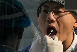 A medical worker collects a sample from a man at a coronavirus testing site in Beijing, Wednesday, Nov. 2, 2022.