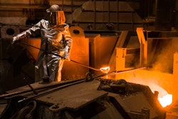 An employee in protective clothing takes a sample from the furnace at the steel producer, Salzgitter AG, in Salzgitter, Germany, Thursday, March 22, 2018.