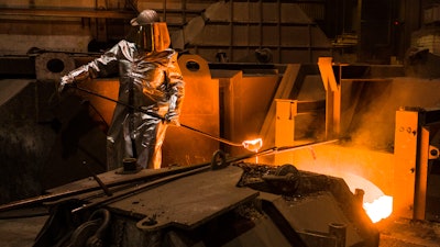 An employee in protective clothing takes a sample from the furnace at the steel producer, Salzgitter AG, in Salzgitter, Germany, Thursday, March 22, 2018.