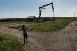 A youth plays near the machine where the sugar cane is weighed in the Lima batey, or neighborhood, in La Romana, where Central Romana Corporation, Ltd. operates its sugar operations in Dominican Republic, Nov. 17, 2021.