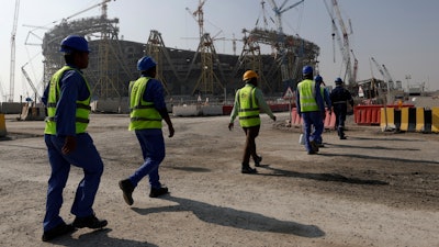 Workers walk to the Lusail Stadium, one of the 2022 World Cup stadiums, in Lusail, Qatar, Friday, Dec. 20, 2019.