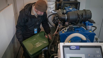 Technician Oleksandr Puhlenko, of Ukrainian mobile telephone network operator Kyivstar, pours gasoline from a jerry can into a tank of a generator for phone tower on the outskirts of Kyiv, Ukraine, Wednesday, Nov. 30, 2022.