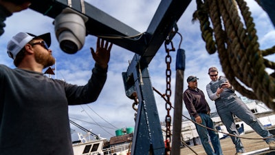 Mark Hager, left, positions a camera with the help of Anthony Lucia, right, as captain Al Cottone watches the feed on a monitor from his boat, the Sabrina Maria, Gloucester, Mass., May 11, 2022.