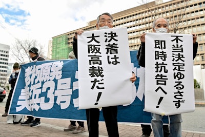 Petitioners display banners in front of Osaka District Court in Osaka, western Japan Tuesday, Dec. 20, 2022.