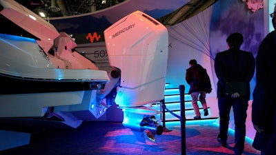 People walk by a Mercury V12 600 HP gas boat motor at the Brunswick booth during the CES tech show Friday, Jan. 6, 2023, in Las Vegas.
