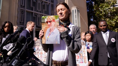 Catherine Berthet, of France, closes her eyes as he holds a photo of her deceased daughter Camille Geoffroy, in front of other families that lost loved ones to crashes of the Boeing 737 Max airliner outside the federal court in Fort Worth, Texas, Thursday, Jan. 26, 2023.