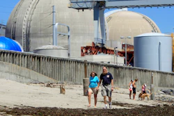 People walk on the sand near the shuttered San Onofre nuclear power plant in San Clemente, Calif., on June 30, 2011.