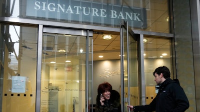 A woman leaves a branch of Signature Bank in New York, March 13, 2023.
