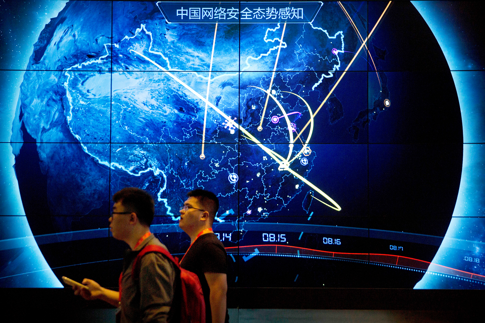 Attendees walk past an electronic display showing recent cyberattacks in China at the China Internet Security Conference in Beijing, on Sept. 12, 2017.