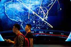 Attendees walk past an electronic display showing recent cyberattacks in China at the China Internet Security Conference in Beijing, on Sept. 12, 2017.
