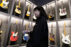 A staff member walks past Fender guitars on display at the opening ceremony of its Tokyo store Thursday, June 29, 2023.