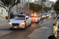 A Waymo driverless taxi stops on a street in San Francisco for several minutes because the back door was not completely shut, while traffic backs up behind it, on Feb. 15, 2023.