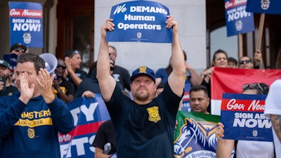 Teamsters union members hold signs urging California Gov. Gavin Newsom to sign Assembly Bill 316 in Sacramento, Sept. 19, 2023.