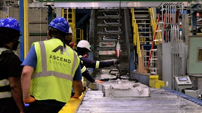 This undated photo provided by Ascend Elements shows team members loading used electric vehicle battery modules onto a massive shredder at the Ascend Elements battery recycling facility in Covington, Ga.