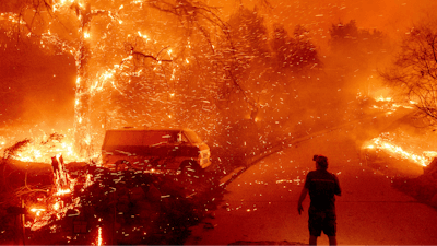 Bruce McDougal watches embers fly over his property as the Bond Fire burns through the Silverado community in Orange County, Calif., Dec. 3, 2020.