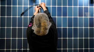 An employee works on a solar panel inside the Hanwha Qcells Solar plant, Monday, Oct. 16, 2023, in Dalton, Ga.