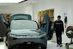 A visitor walks near the P7i electric sedan from Chinese automaker Xpeng at a show room in Beijing, Thursday, April 13, 2023.