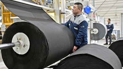 Workers produce car mats in a factory of car interior pieces in Yantai in east China's Shandong province, on Feb. 21, 2024.
