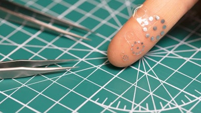 Three variations of the ultrasound sticker displayed on a fingertip for scale.